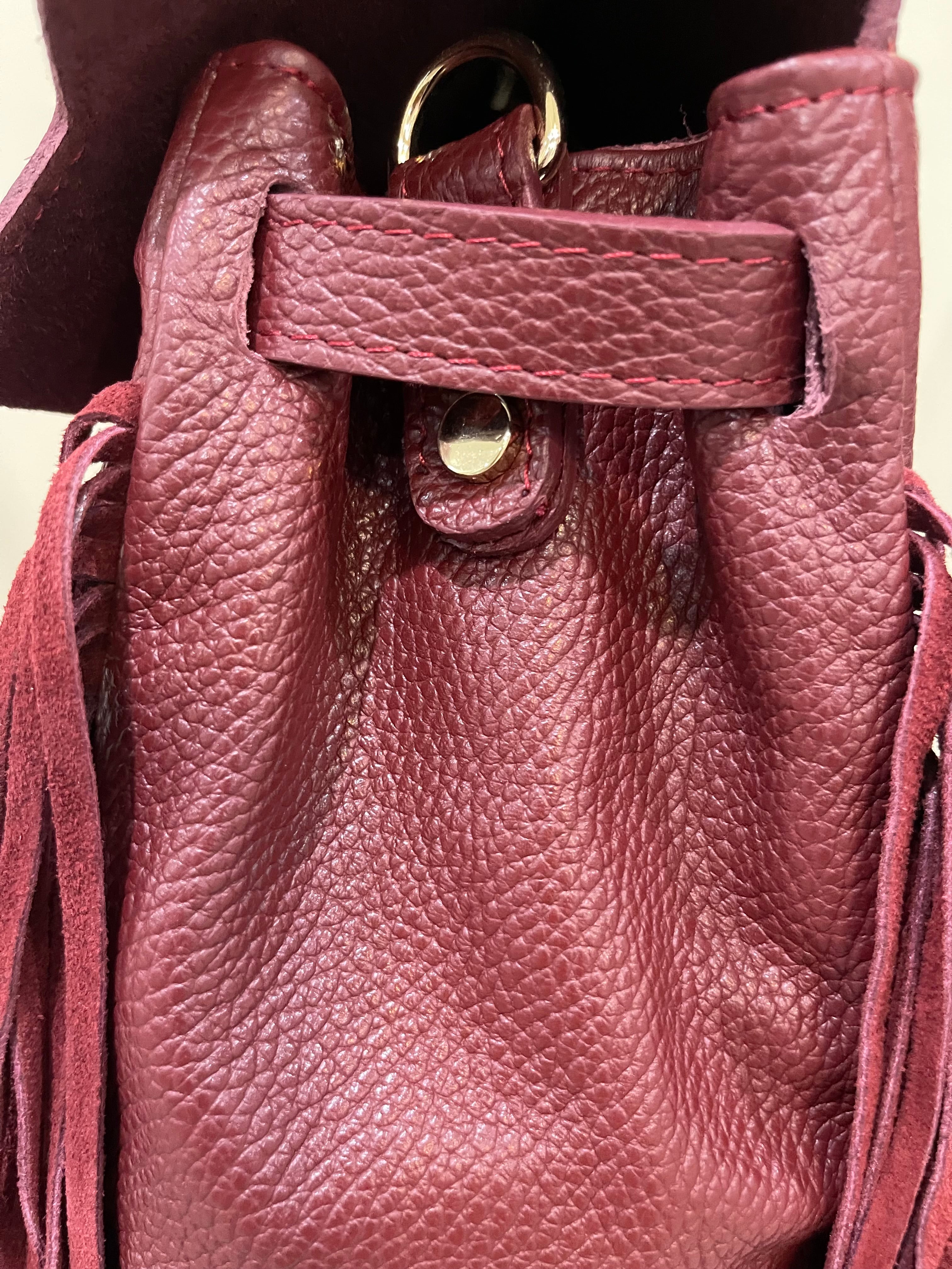 GOLDxTEAL gorgeous timeless pebbled grained leather satchel with fringe in the color Bordeaux.