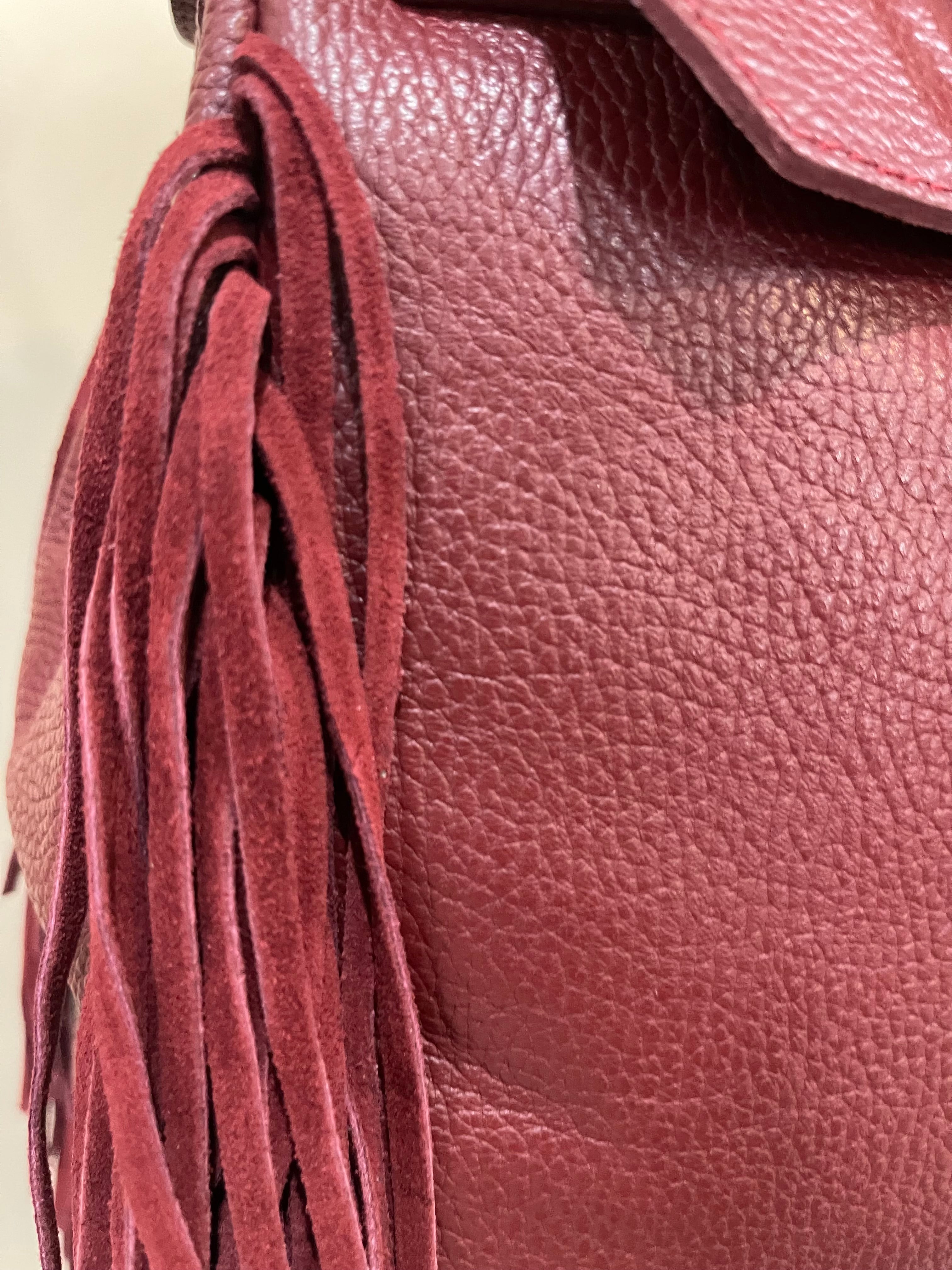 GOLDxTEAL gorgeous timeless pebbled grained leather satchel with fringe in the color Bordeaux.