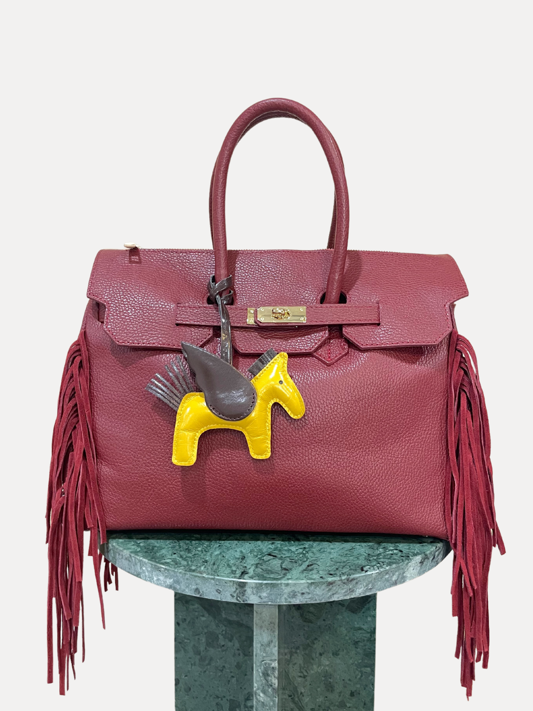GOLDxTEAL gorgeous timeless pebbled grained leather satchel with fringe in the color Bordeaux.