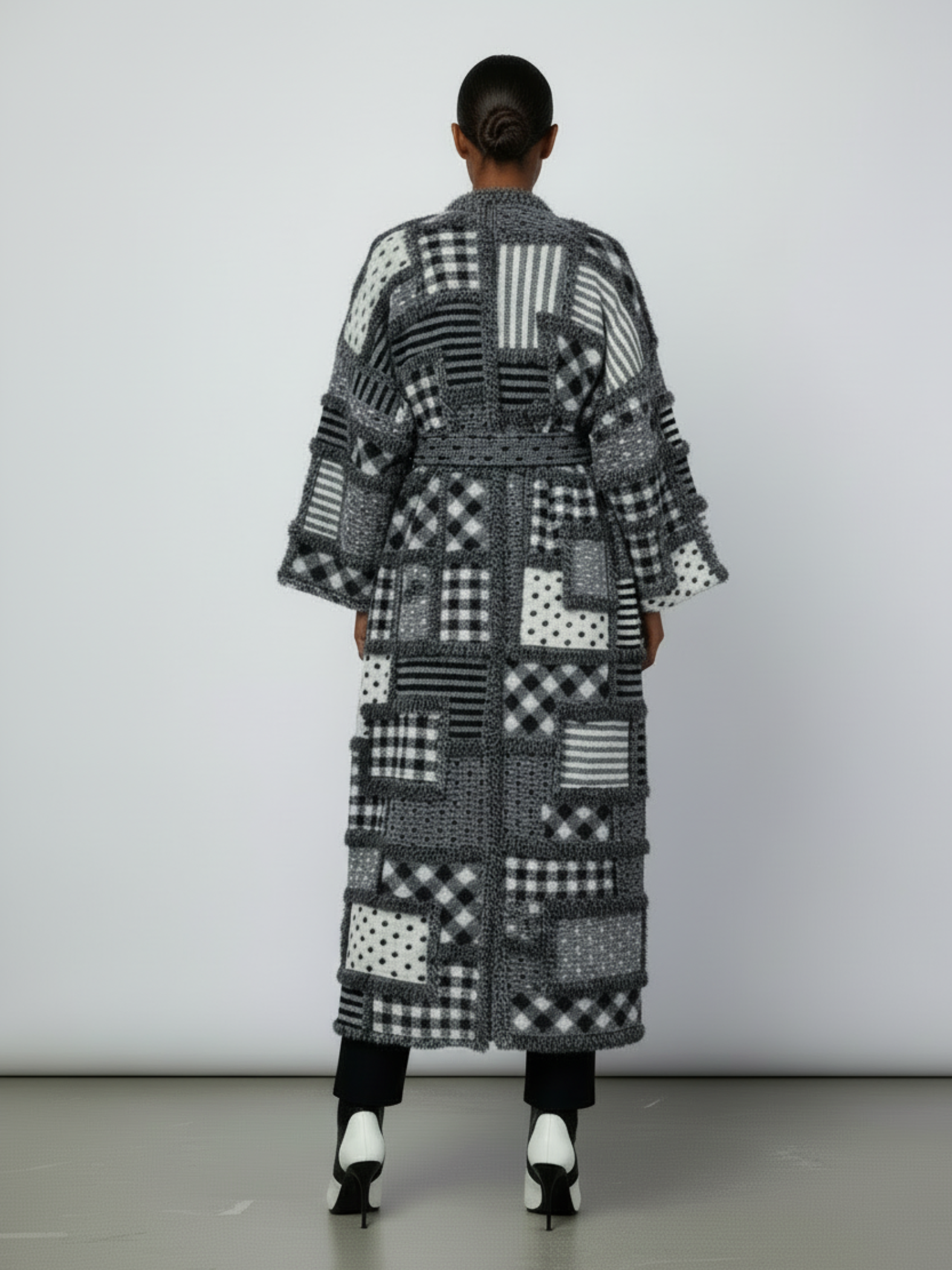 GOLDxTEAL Back view of the Noir Mosaic Duster featuring the full-length patchwork design and thick textured knit pattern in black, white, and grey.