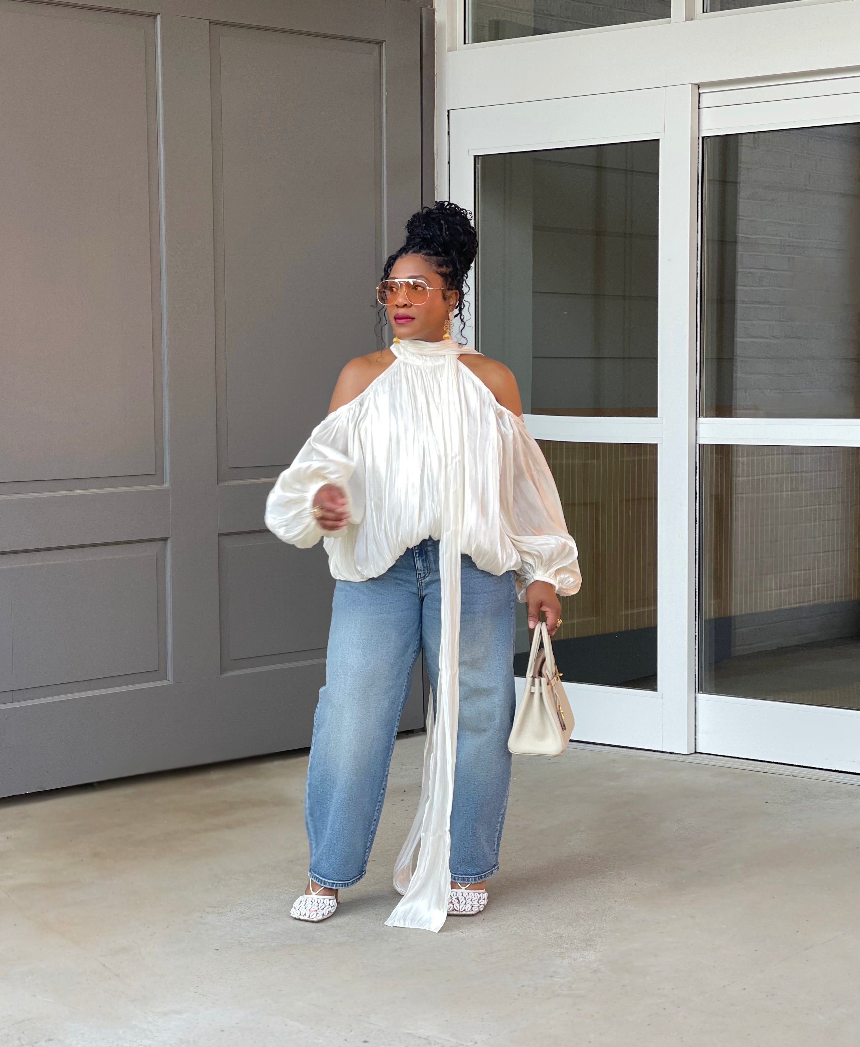 Model in front of a building wearing a GOLDxTEAL gorgeous cream billowy balloon top with cold shoulder cut outs and optional scarf.