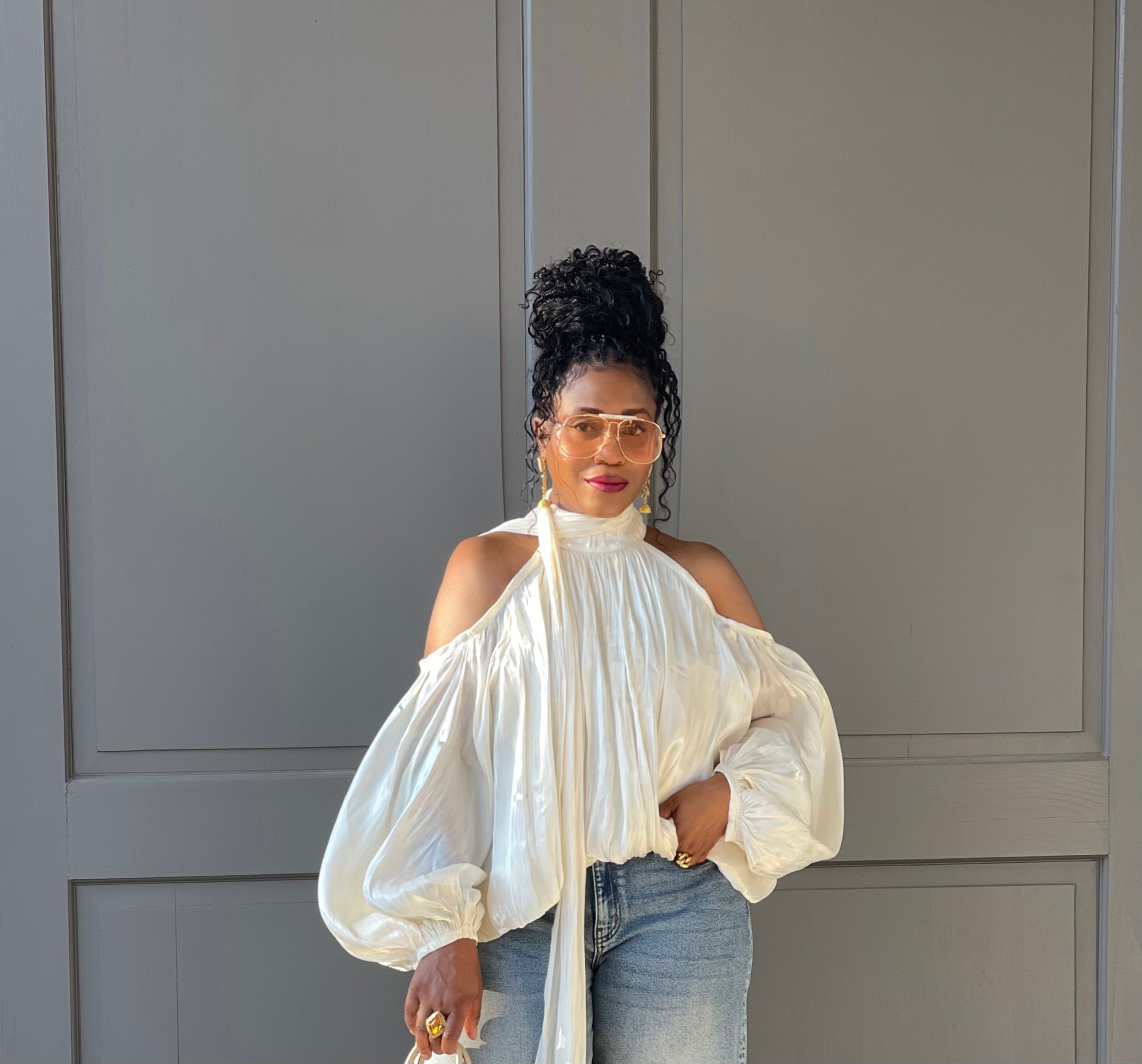 Model in front of a building wearing a GOLDxTEAL gorgeous cream billowy balloon top with cold shoulder cut outs and optional scarf.