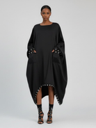 GOLD x TEAL oversized black cocoon dress with silver grommet pocket detail, front view. 