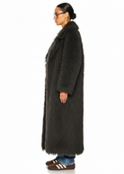 Side profile of the GOLD x TEAL Mocha Opulence Coat showing plush mocha faux Mongolian fur and long silhouette.