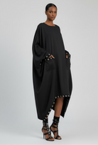 Draped oversized black dress with boat neckline and grommet-trim pockets.
