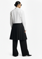 Back view of GOLD x TEAL Monarch Pleat Trousers highlighting pleated skirt overlay and full wide-leg pant silhouette.