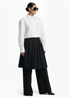 Side profile of the GOLD x TEAL Monarch Pleat Trousers featuring structured pleated skirt overlay and wide-leg design.