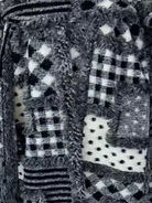 GOLDxTEAL Detailed close-up of the Noir Mosaic Duster’s black and white patchwork knit pattern with textured stitching and woven design.