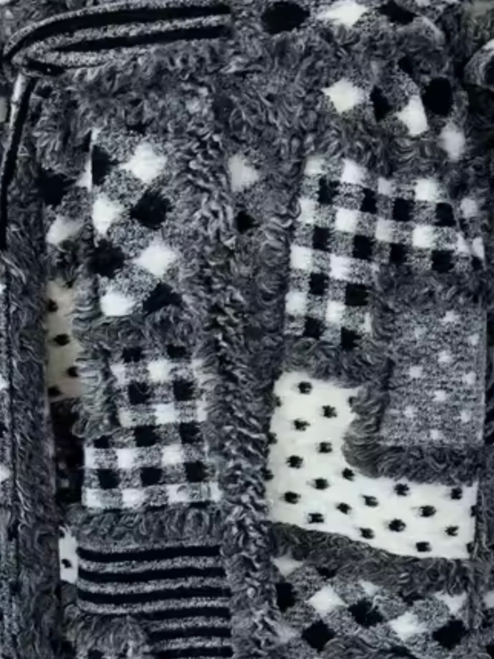 GOLDxTEAL Detailed close-up of the Noir Mosaic Duster’s black and white patchwork knit pattern with textured stitching and woven design.