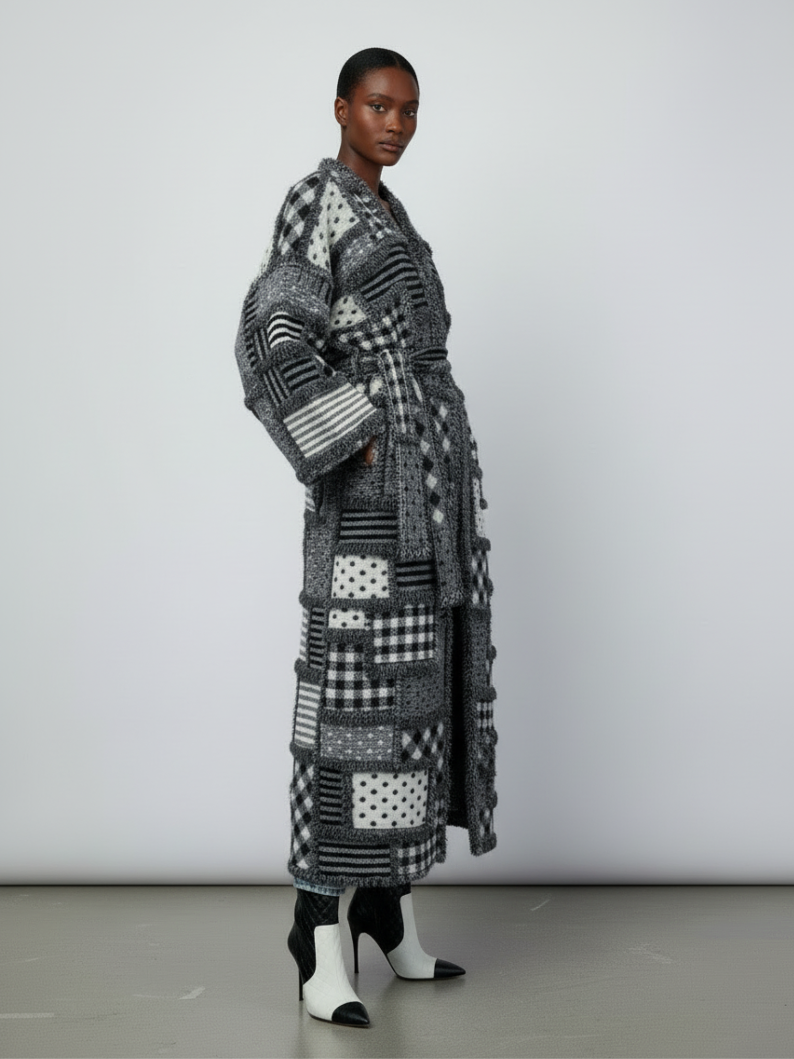 GOLDxTEAL Side view of the Noir Mosaic Duster showcasing the kimono sleeves, long draped silhouette, and detailed monochrome knit patchwork texture.
