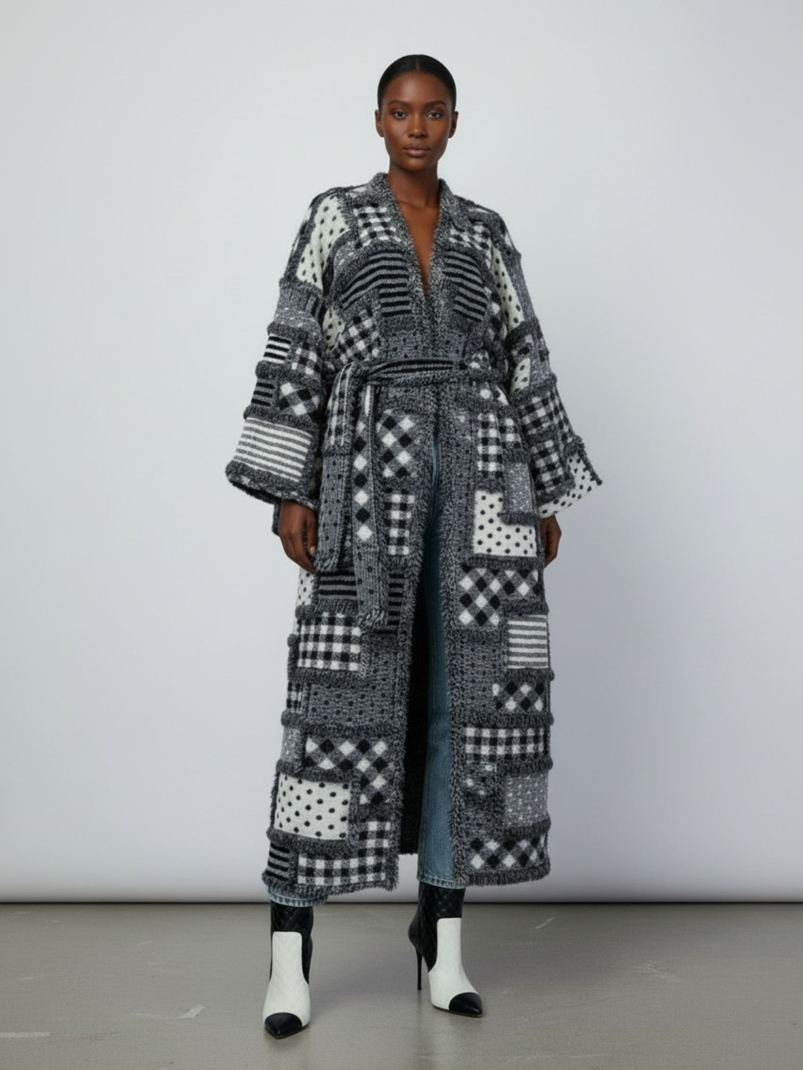 GOLDxTEAL Front view of the Noir Mosaic Duster, a thick knit patchwork coat with kimono sleeves and optional waist belt in black and white textured patterns.