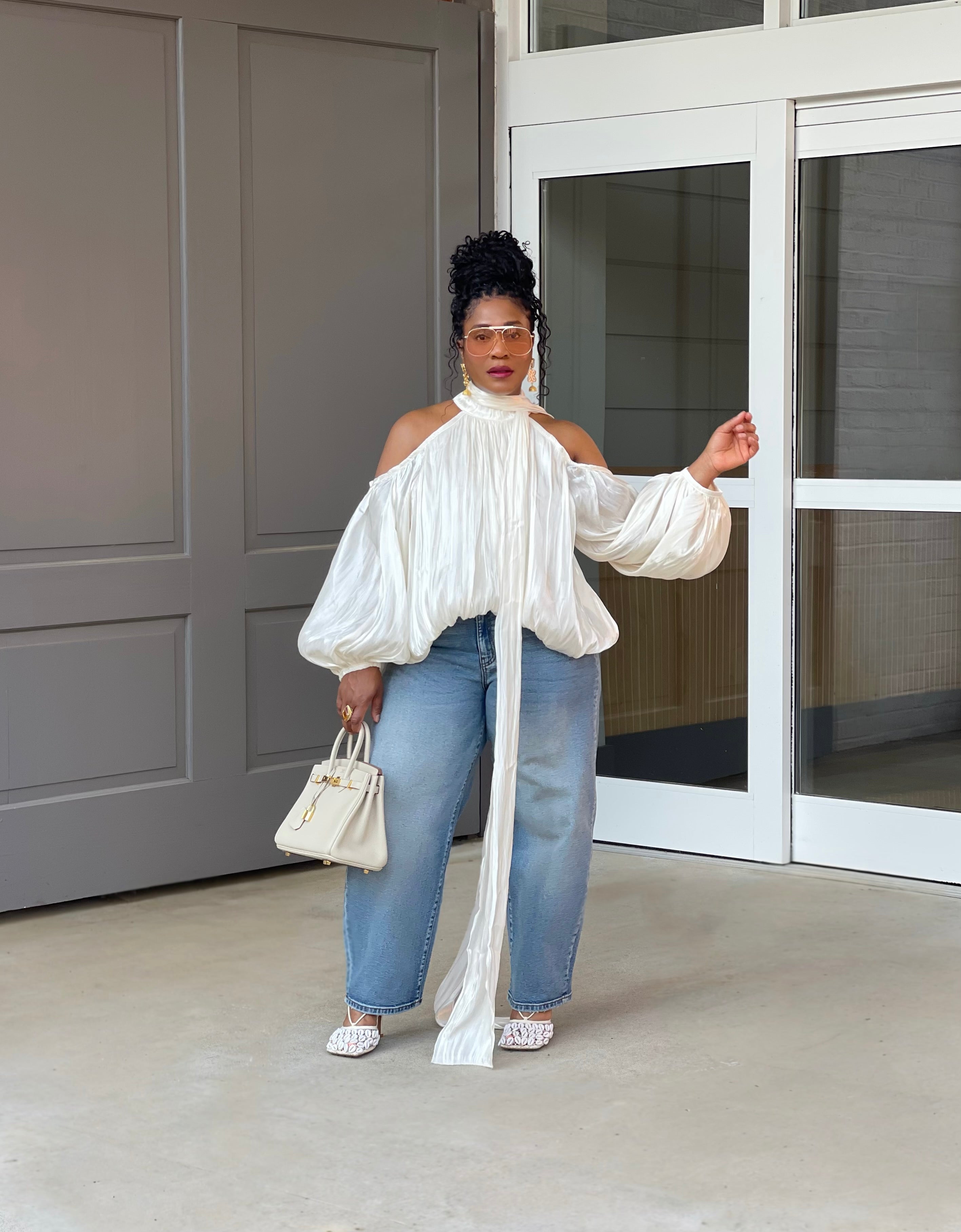 Model in front of a building wearing a GOLDxTEAL gorgeous cream billowy balloon top with cold shoulder cut outs and optional scarf. 