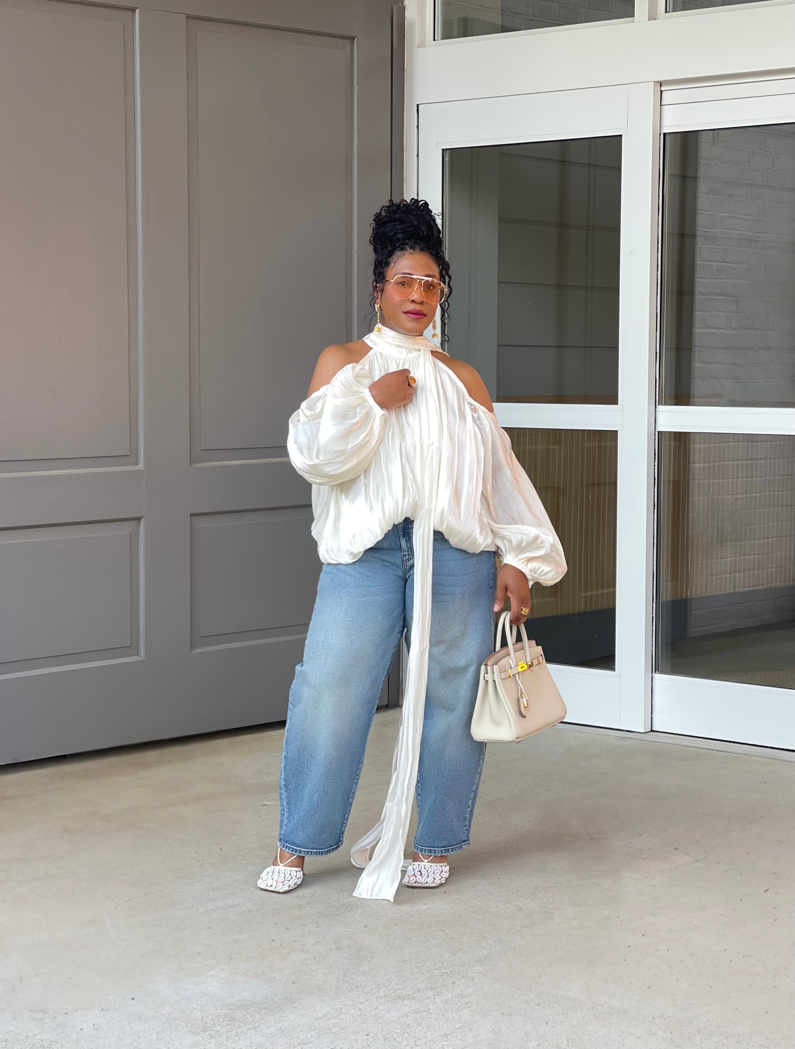 Model in front of a building wearing a GOLDxTEAL gorgeous cream billowy balloon top with cold shoulder cut outs and optional scarf. 