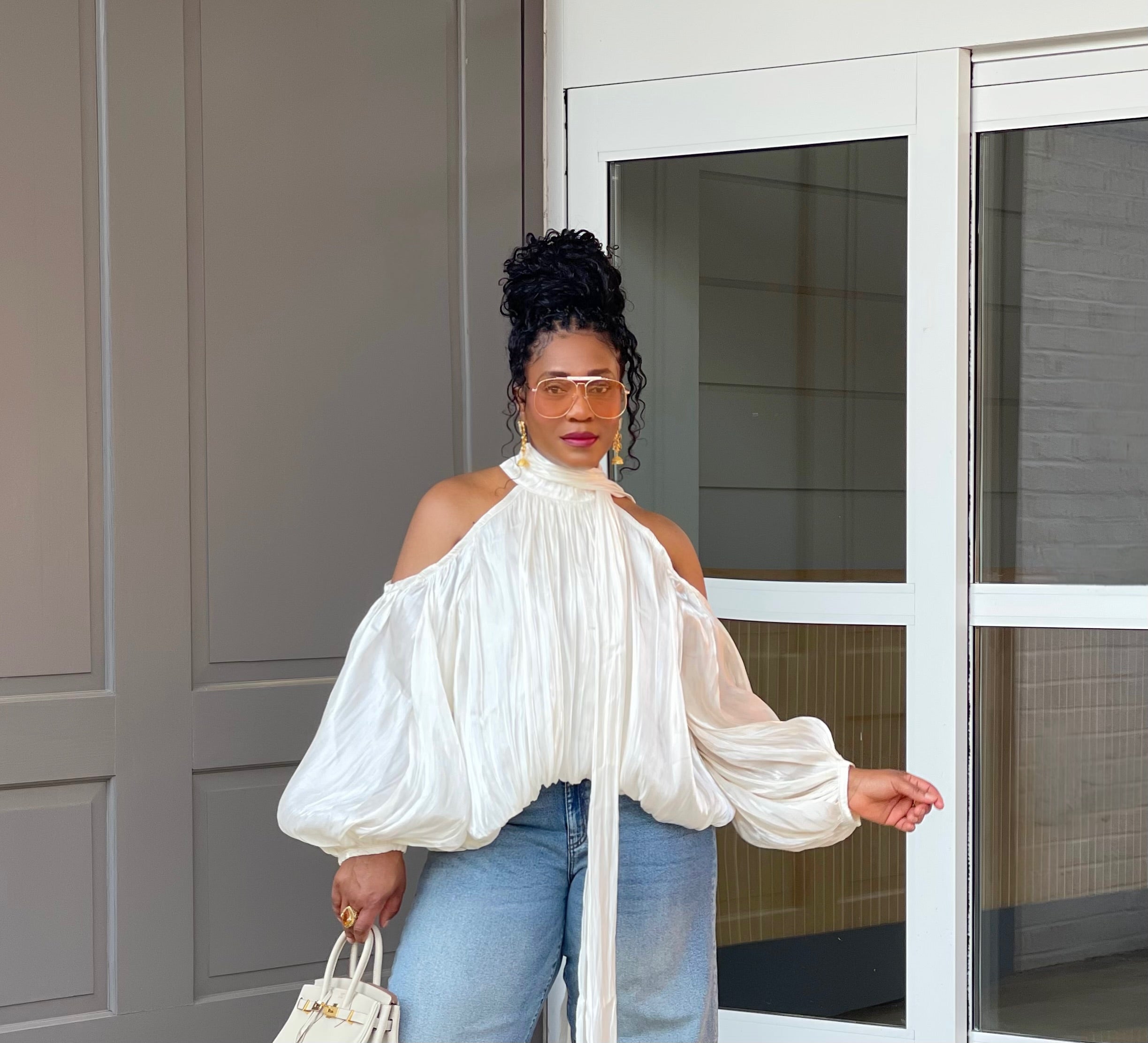 Model in front of a building wearing a GOLDxTEAL gorgeous cream billowy balloon top with cold shoulder cut outs and optional scarf. 