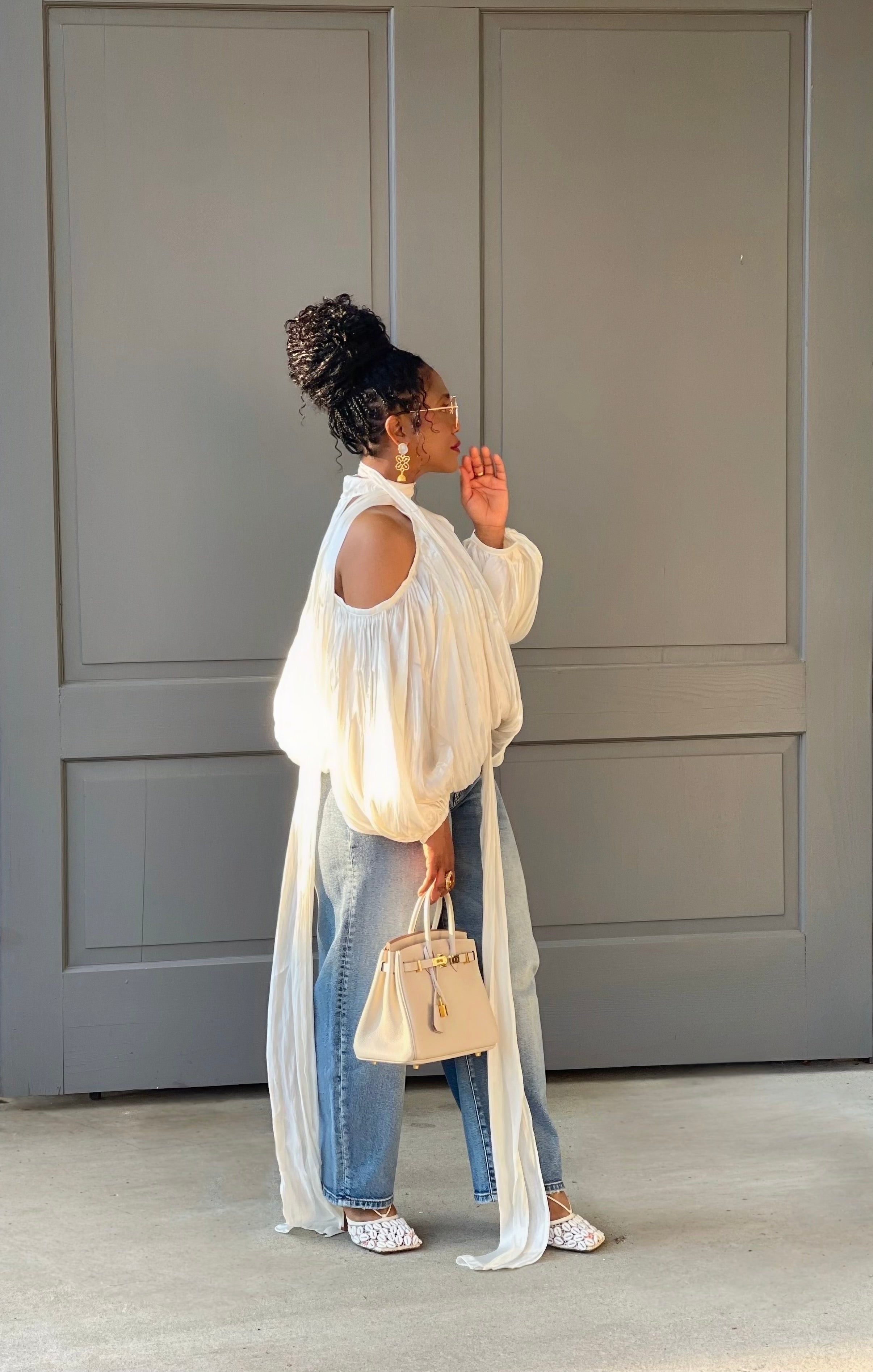Model in front of a building wearing a GOLDxTEAL gorgeous cream billowy balloon top with cold shoulder cut outs and optional scarf. 