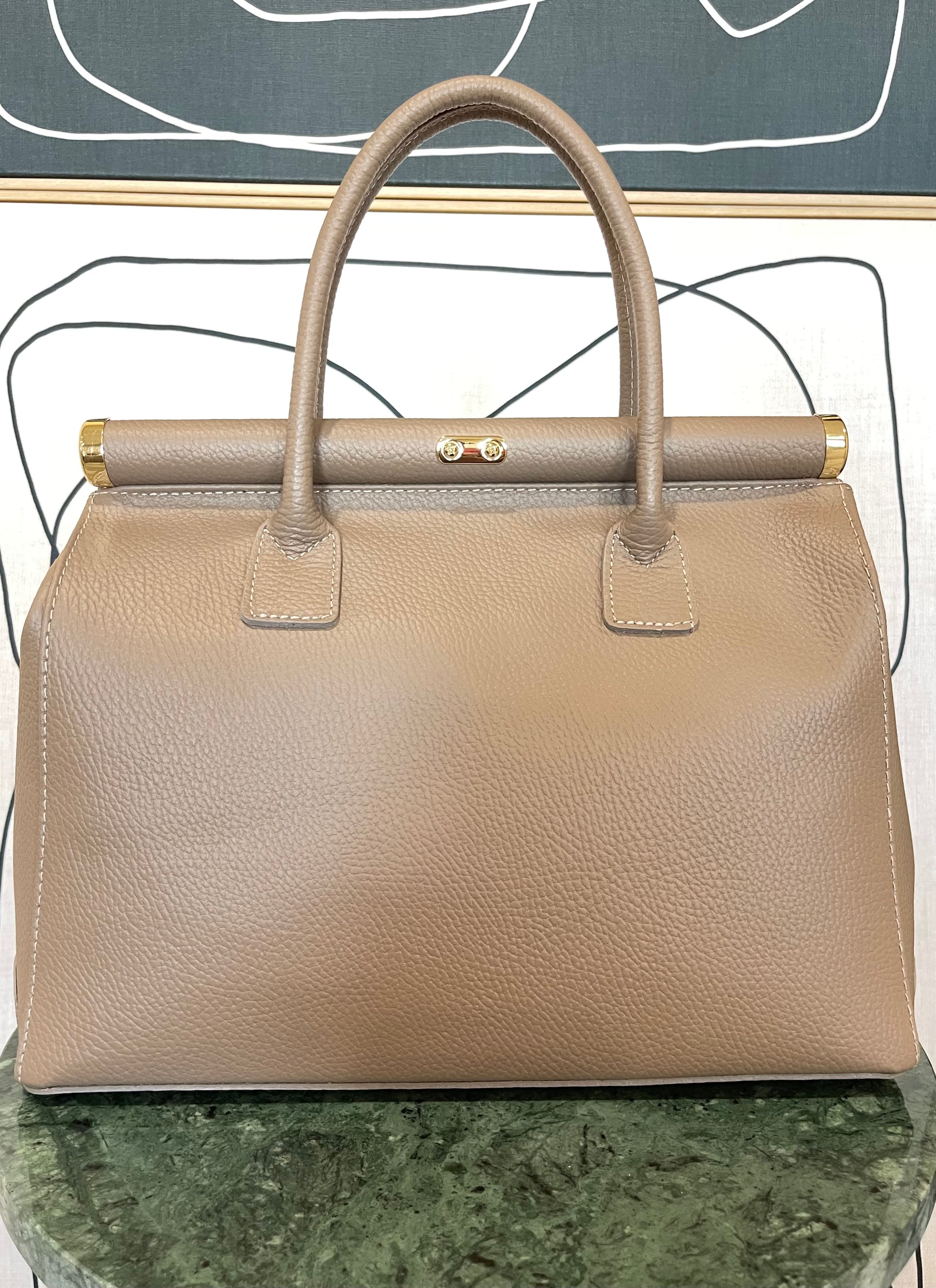 GOLDxTEAL gorgeous taupe leather handbag with gold tone lock.