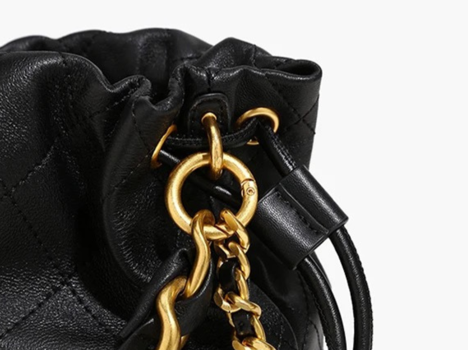 GOLDxTEAL black leather mini bucket bag with a gold woven chain handle.